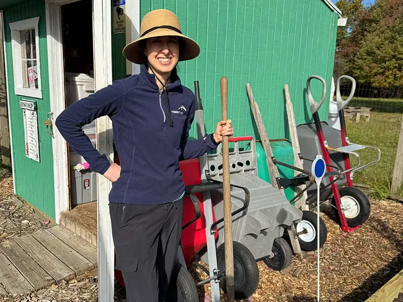 woman with a shovel standing in front of wheel barrows